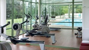 Un gimnasio con máquinas de cardio y vistas a una piscina.