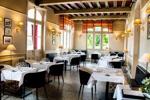 Un restaurante con varias mesas, sillas y un techo con vigas a la vista.