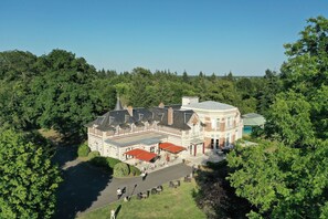 A large, historic building with a central courtyard, surrounded by lush greenery.