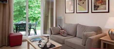 A living room with a sofa, a coffee table, and a tennis racket. There are three framed pictures on the wall.