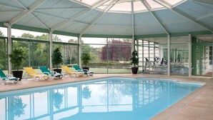Una piscina interior con sillones de descanso y bicicletas estáticas.