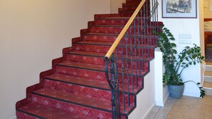 A staircase with red carpeted steps and a black railing, leading to an upper floor. - Alexa Old Town (Vilnius)