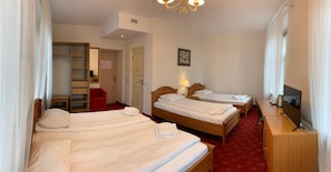 A hotel room with three single beds, a TV, a desk, and a red chair. - Alexa Old Town (Vilnius)