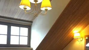 A room with a sloped ceiling, a bed with white linens, a wooden headboard, a bedside table with a lamp, and a radiator. - Alexa Old Town (Vilnius)