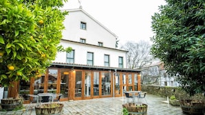 Un bâtiment doté d’un patio couvert, de meubles en bois et de plantes en pot.