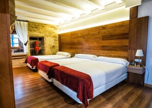 Une chambre d’hôtel avec deux lits, un plancher en bois, un mur en pierre et un luminaire moderne au plafond.