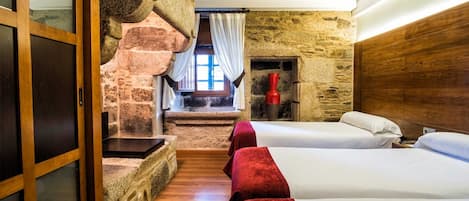 Una habitación con pared de piedra, escalera de madera y cama con ropa de cama roja.