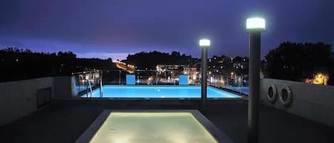 Een buitenzwembad, een zwembad op het dak en parasols bij het zwembad