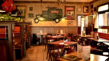 A restaurant interior with wooden tables and chairs, a vintage truck decoration, and a red booth seating area.