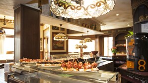 A buffet with various food items, a coffee machine, and a decorative glass ceiling. - El Volante (Ciempozuelos)
