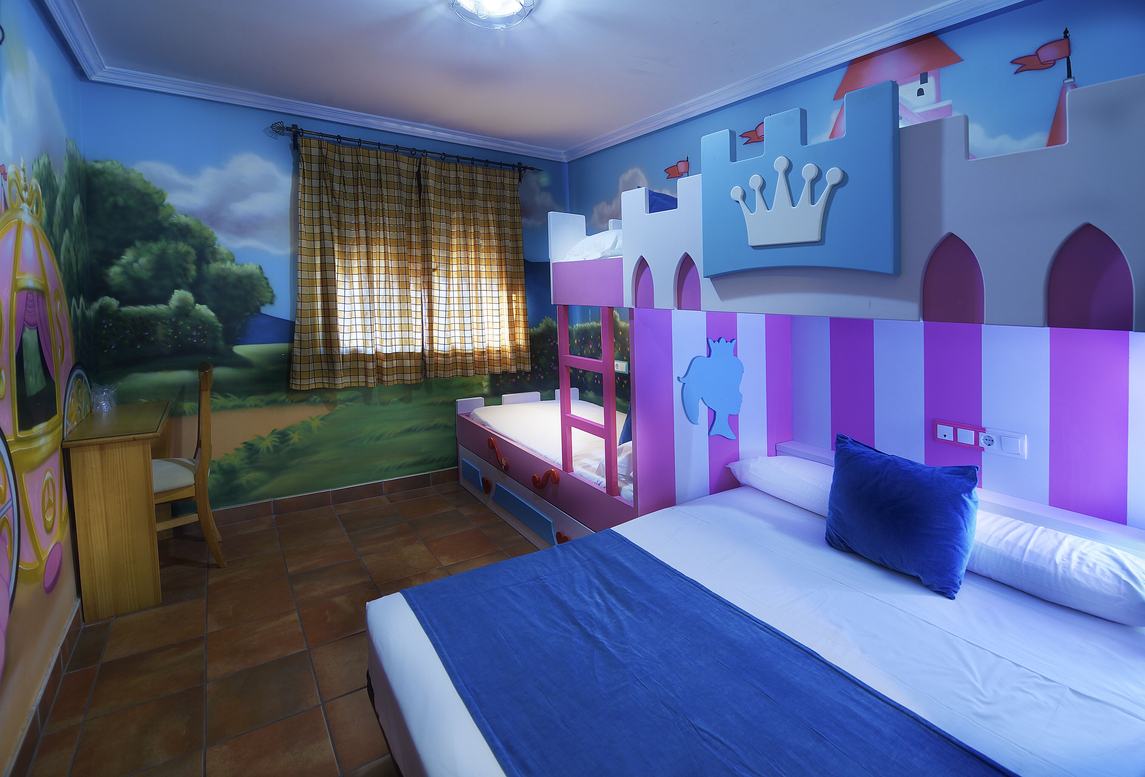 A bedroom with a mural of a castle, a bed with a blue bedspread, and a window with a checkered curtain.
