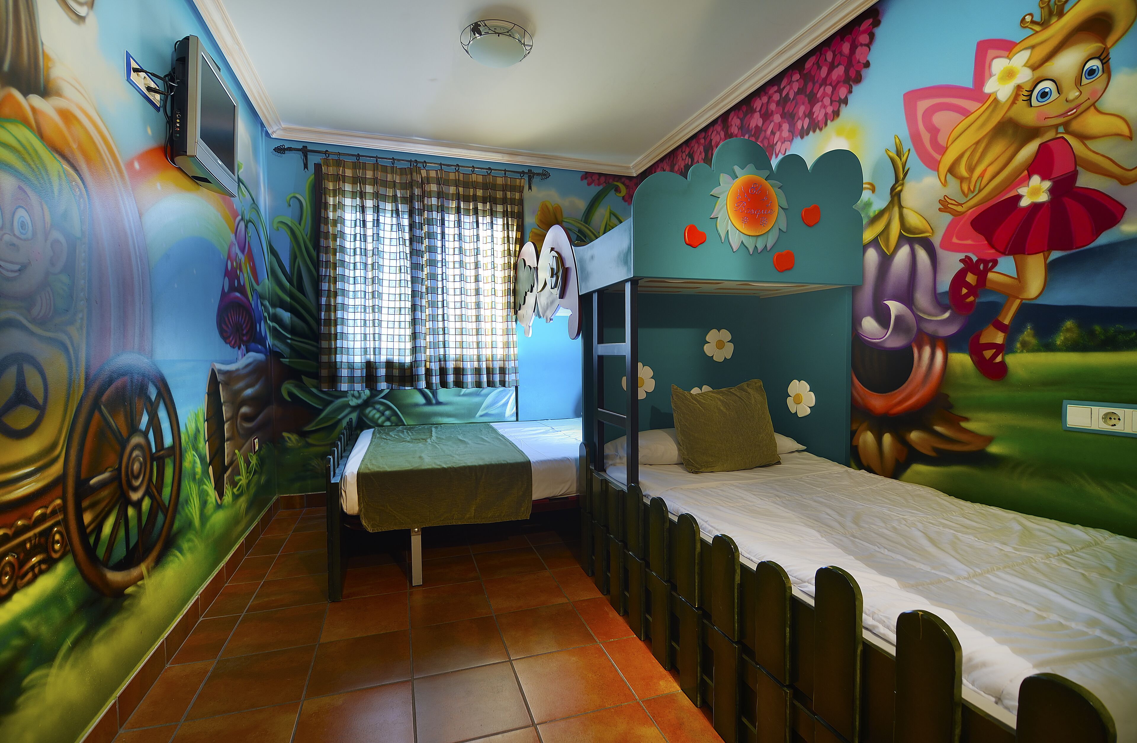 Una habitación con literas, un mural, una ventana con cortinas y un televisor.