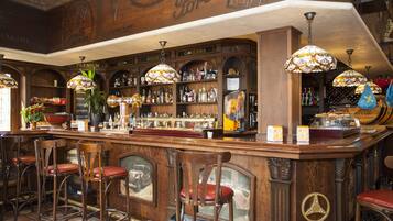 A bar area with wooden bar counter, multiple stools, and hanging lamps.