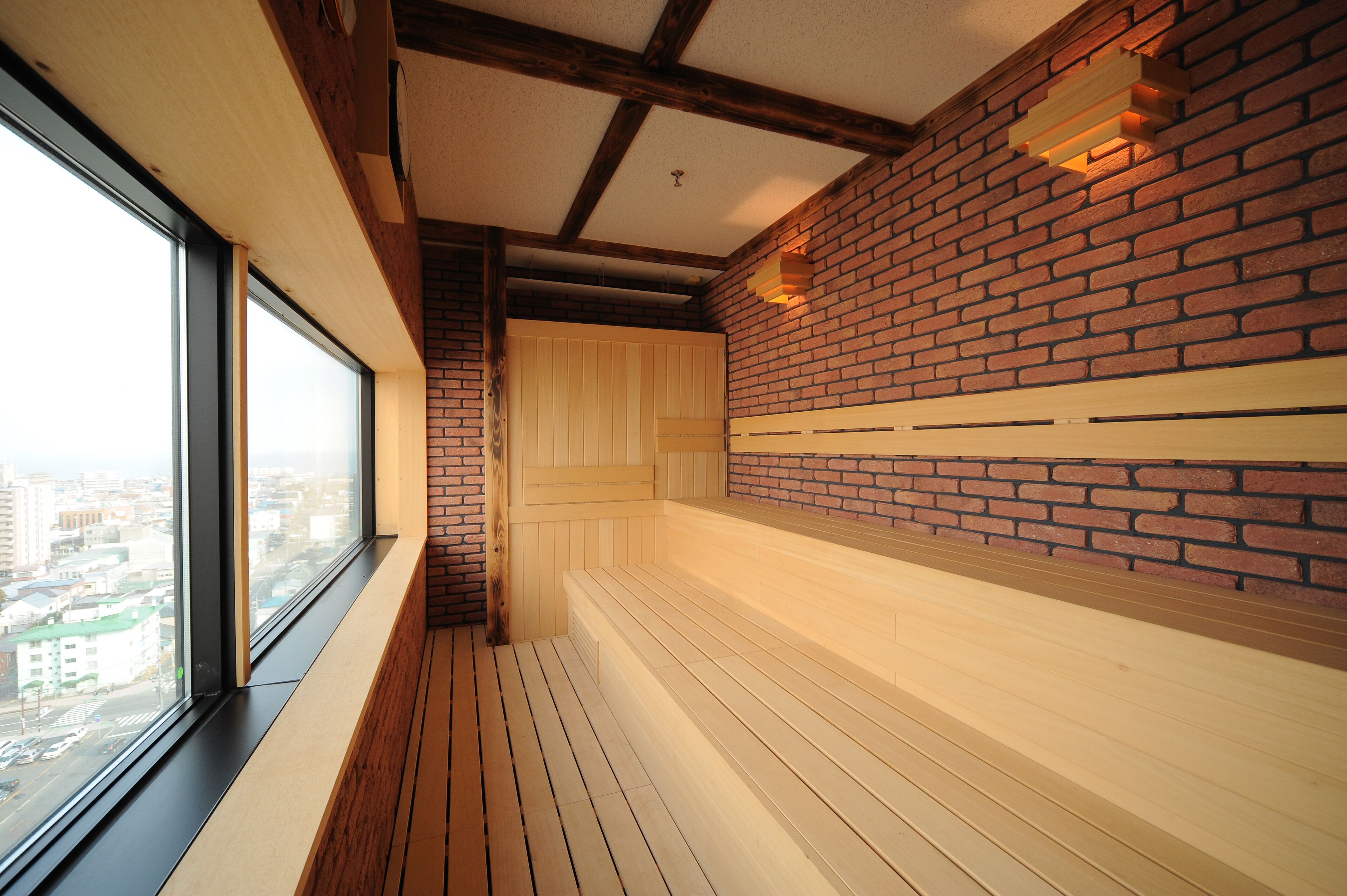 A room with a wooden floor, a brick wall, and a large window.