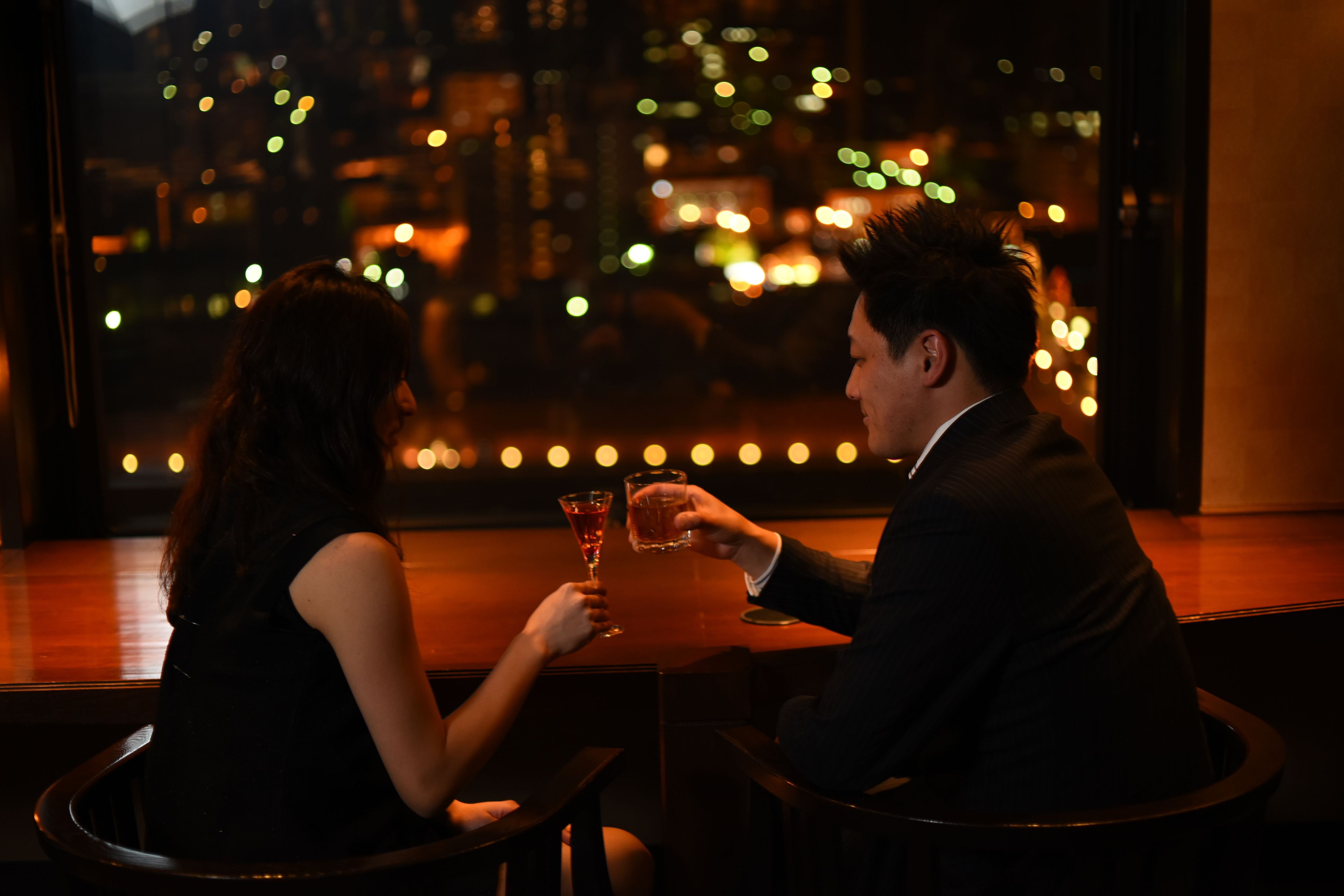 Una pareja sentada en una mesa con vistas a la ciudad a través de una ventana.