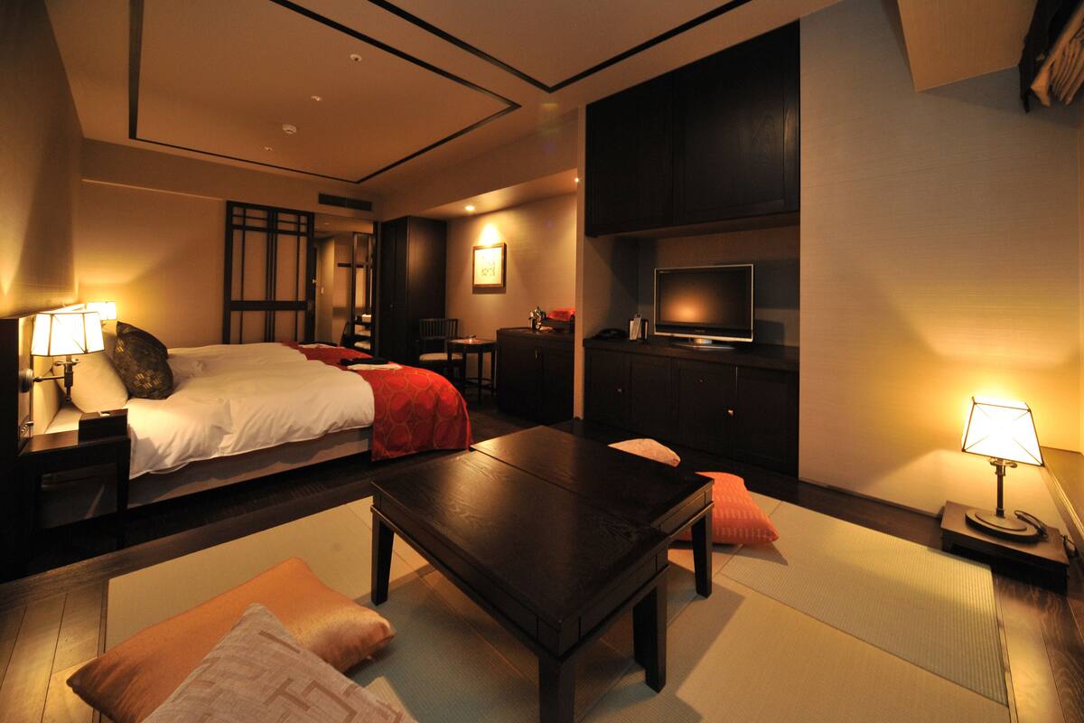 Una habitación de hotel con cama, escritorio, televisión y sofá.