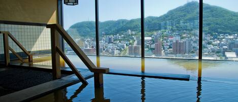 An indoor swimming pool with a view of a cityscape and mountains.