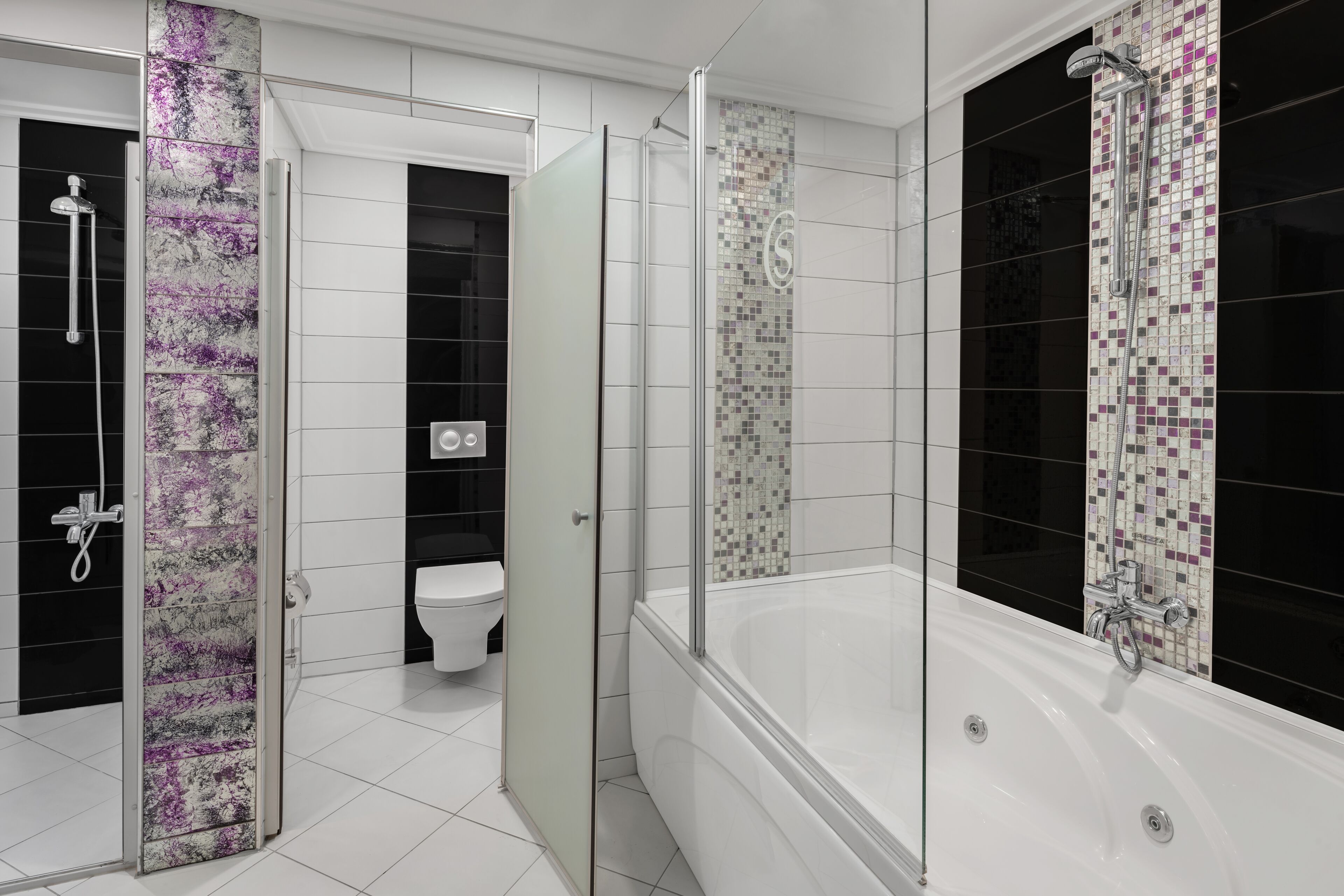 Un baño moderno con ducha de vidrio, bañera independiente y un inodoro al fondo.