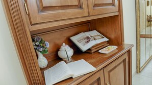 Een houten bureau met een boek, een vaas met bloemen en een decoratief bord.