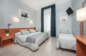 Habitación de hotel con dos camas, una mesita de noche, una planta en maceta y un televisor montado en la pared.