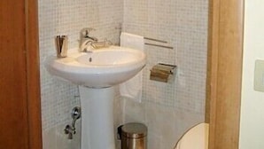 Une salle de bain avec un lavabo blanc, un miroir et des murs carrelés.