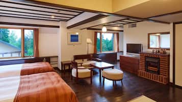 A hotel room with two beds, a desk, a chair, a television, a fireplace, and large windows with curtains.