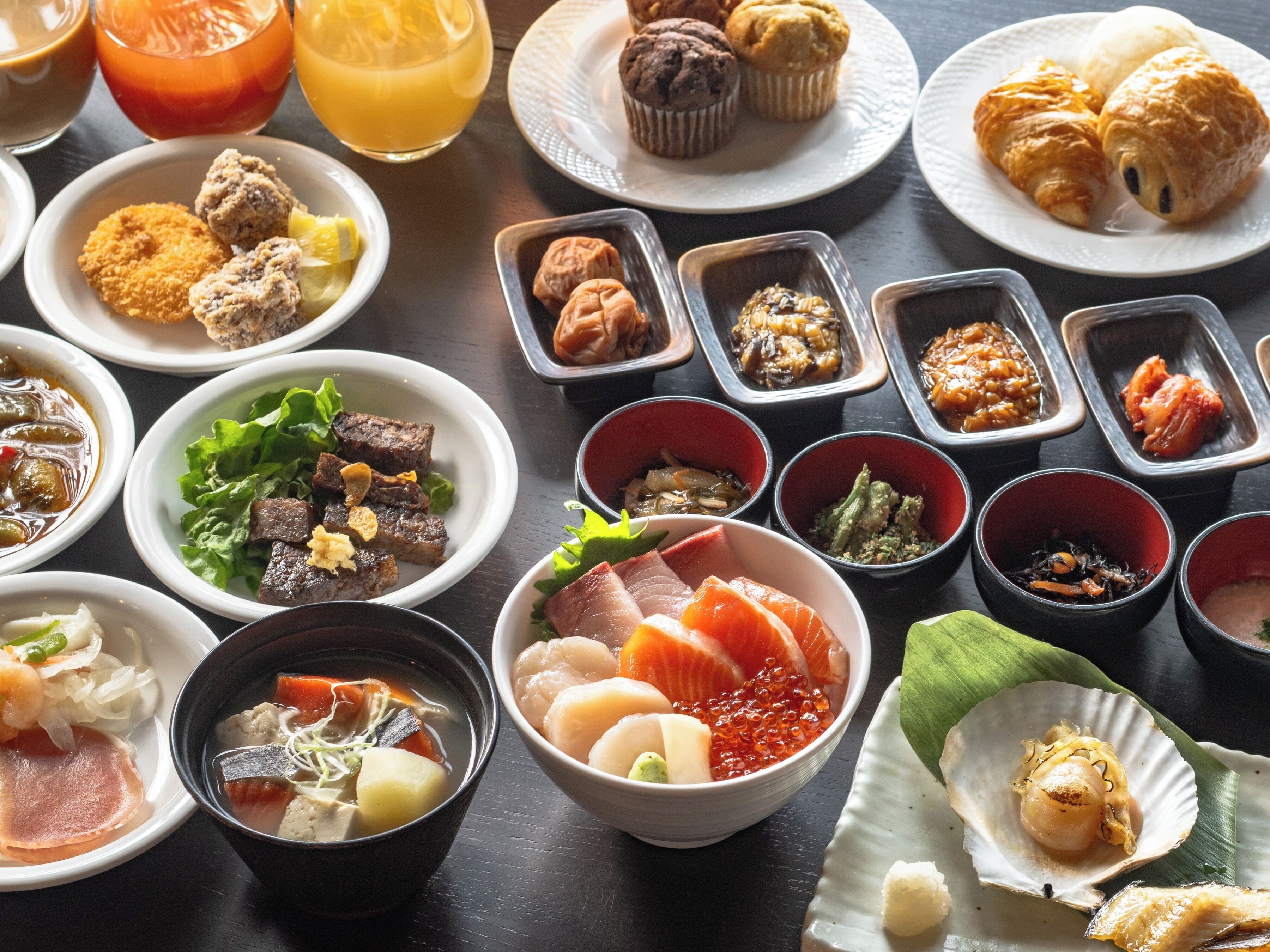 A variety of dishes including sushi, sashimi, and other Asian cuisine, arranged on a table.
