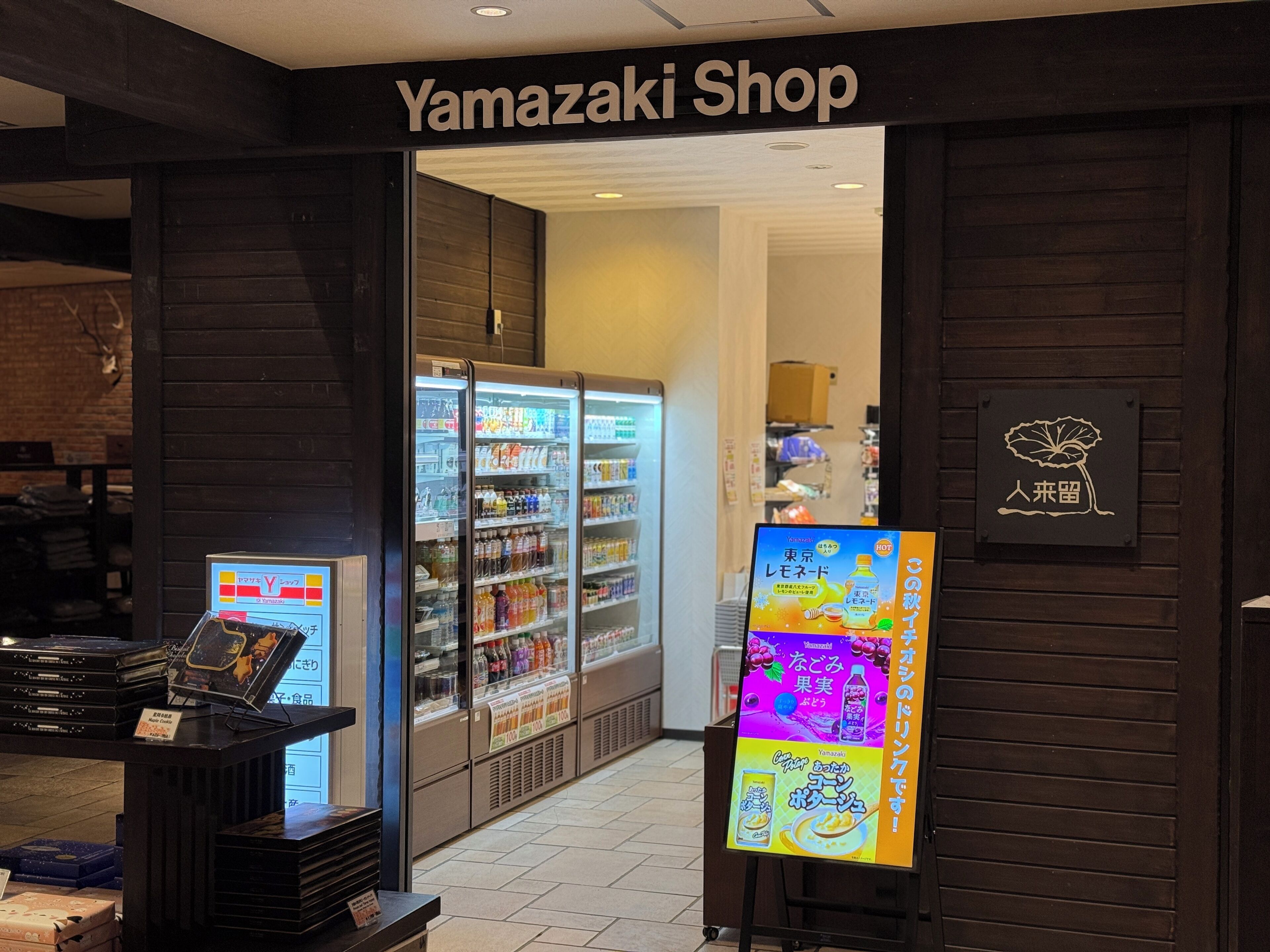 The entrance to a Yamazaki Shop with refrigerated beverage displays and a digital menu board.