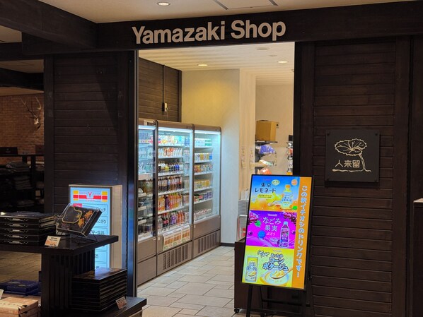 The entrance to a Yamazaki Shop with refrigerated beverage displays and a digital menu board. - La Vista Daisetsuzan (Higashikawa)