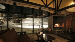 Un interior acogedor con chimenea, zona de estar y un ventanal con vistas a un paisaje nevado.