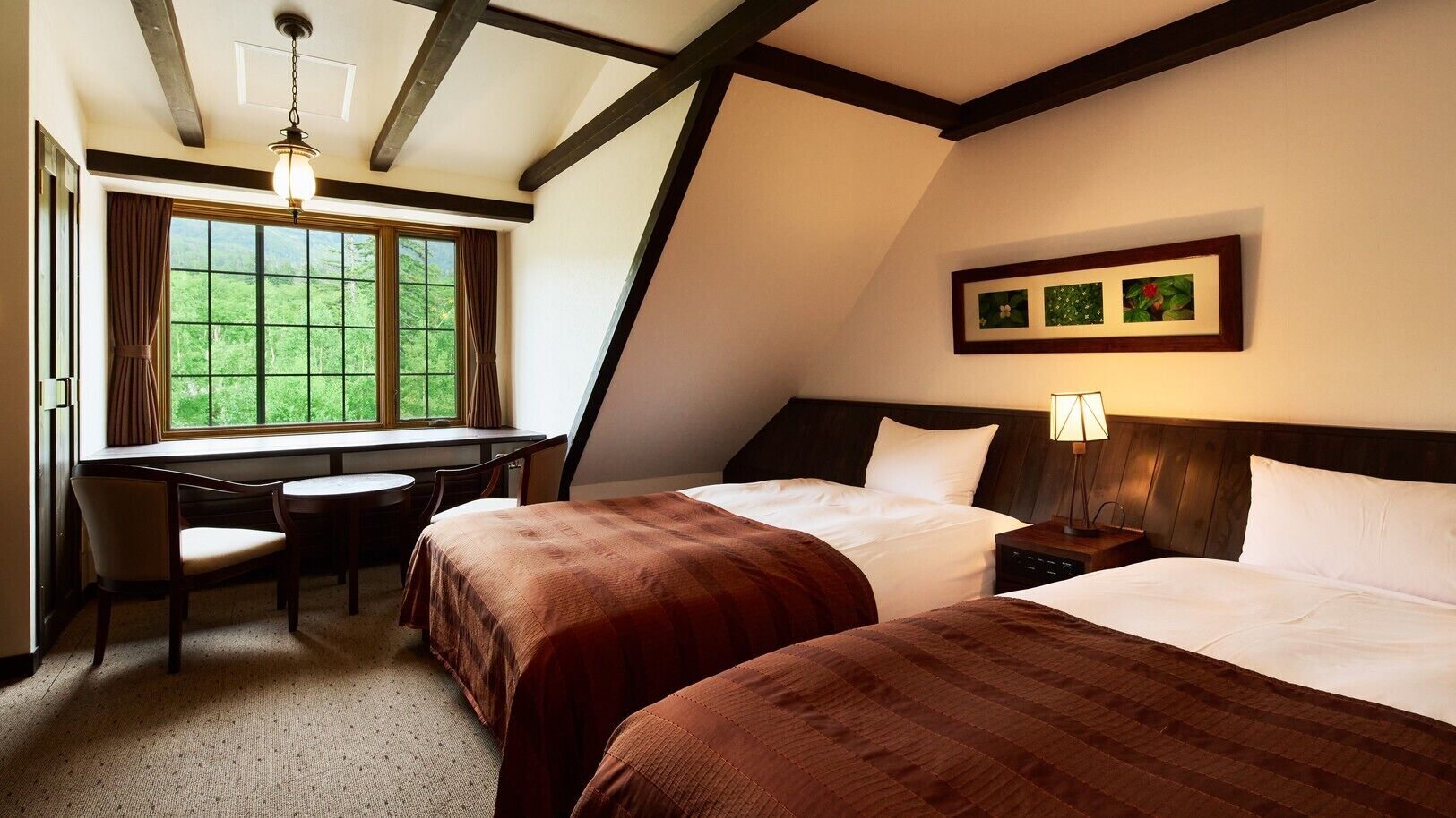 Een hotelkamer met twee bedden, een bureau en een raam met gordijnen.
