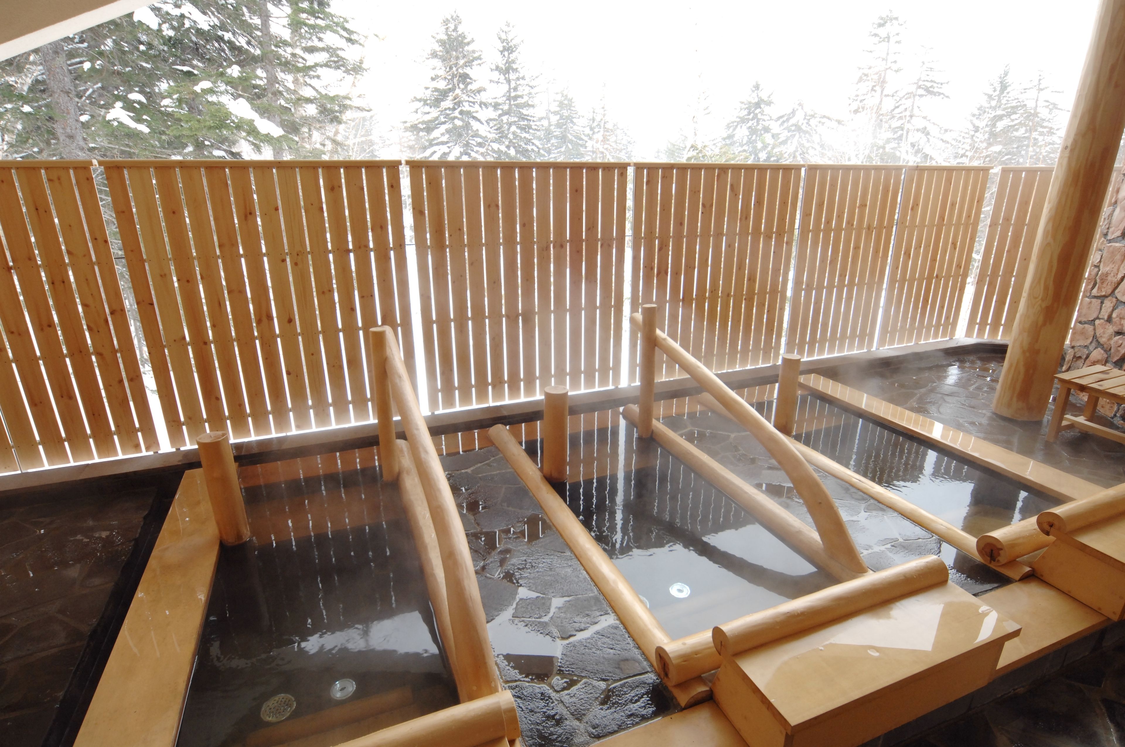 A hot spring bath area with wooden railings and stone flooring.