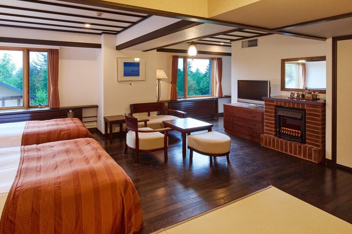 Habitación de hotel con dos camas, un escritorio, una silla, un televisor y una chimenea.