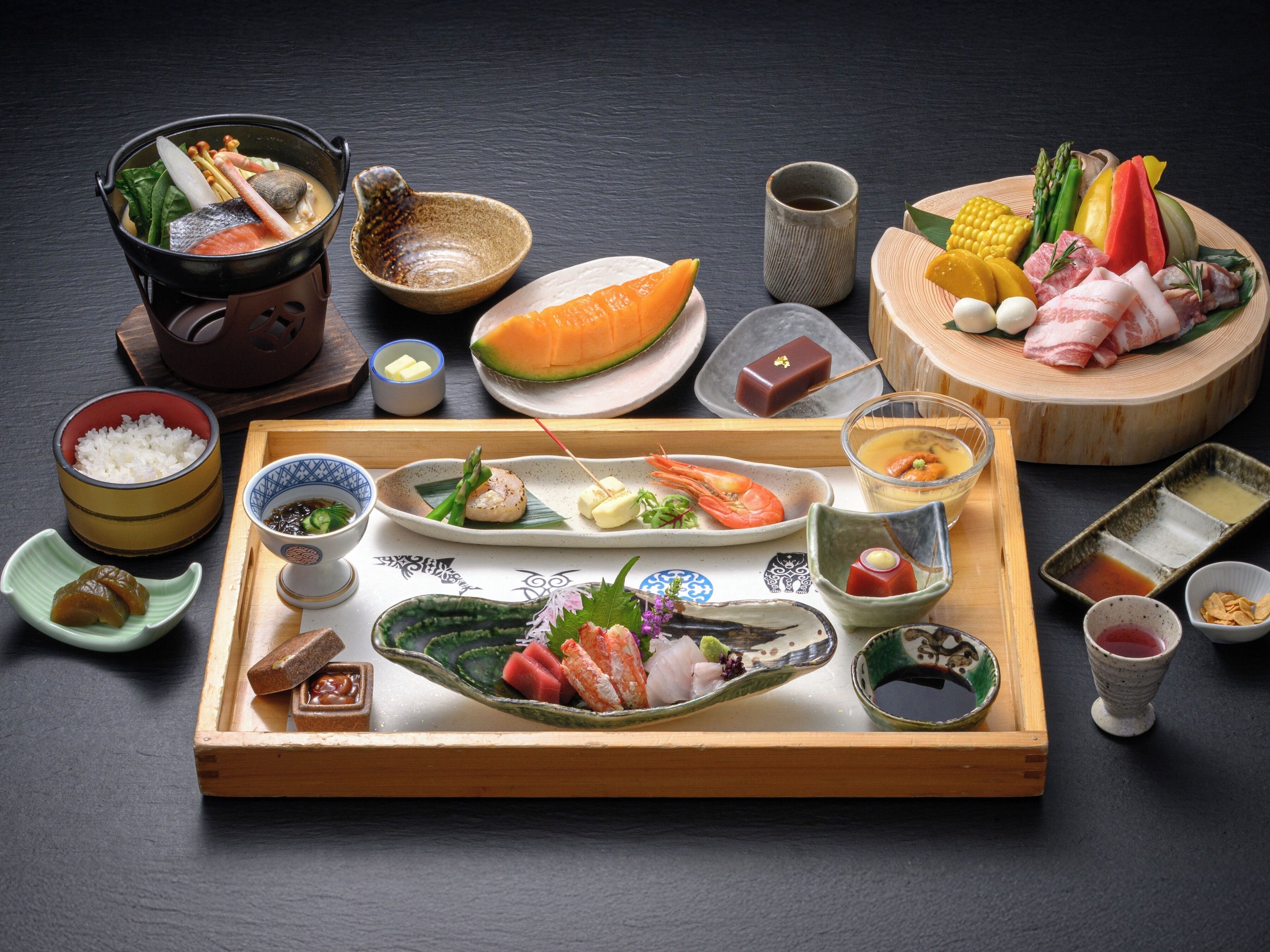 Une variété de plats japonais, notamment des sushis, des sashimis et un plat mijoté, présentés sur un plateau en bois.