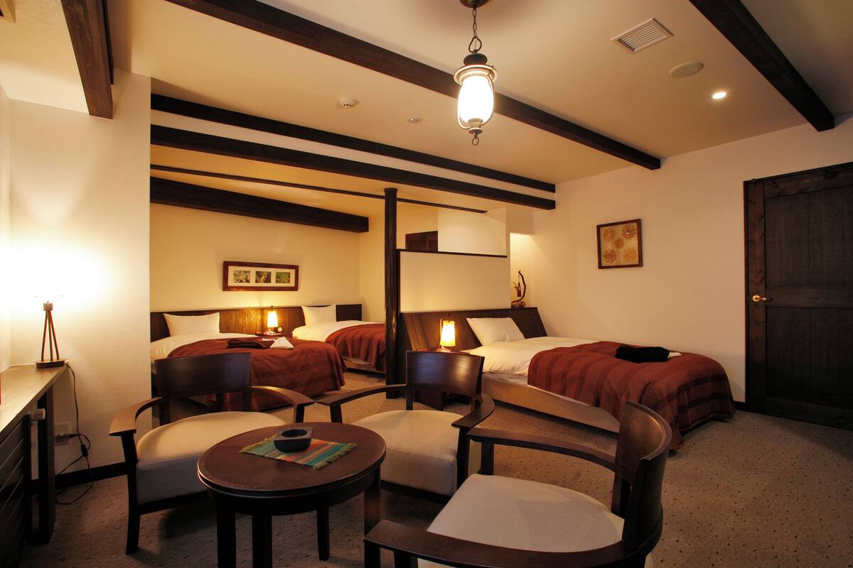 Une chambre d’hôtel avec deux lits, un bureau et deux fauteuils.