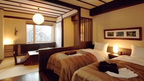 Habitación de hotel con dos camas, un escritorio y un ventanal amplio.