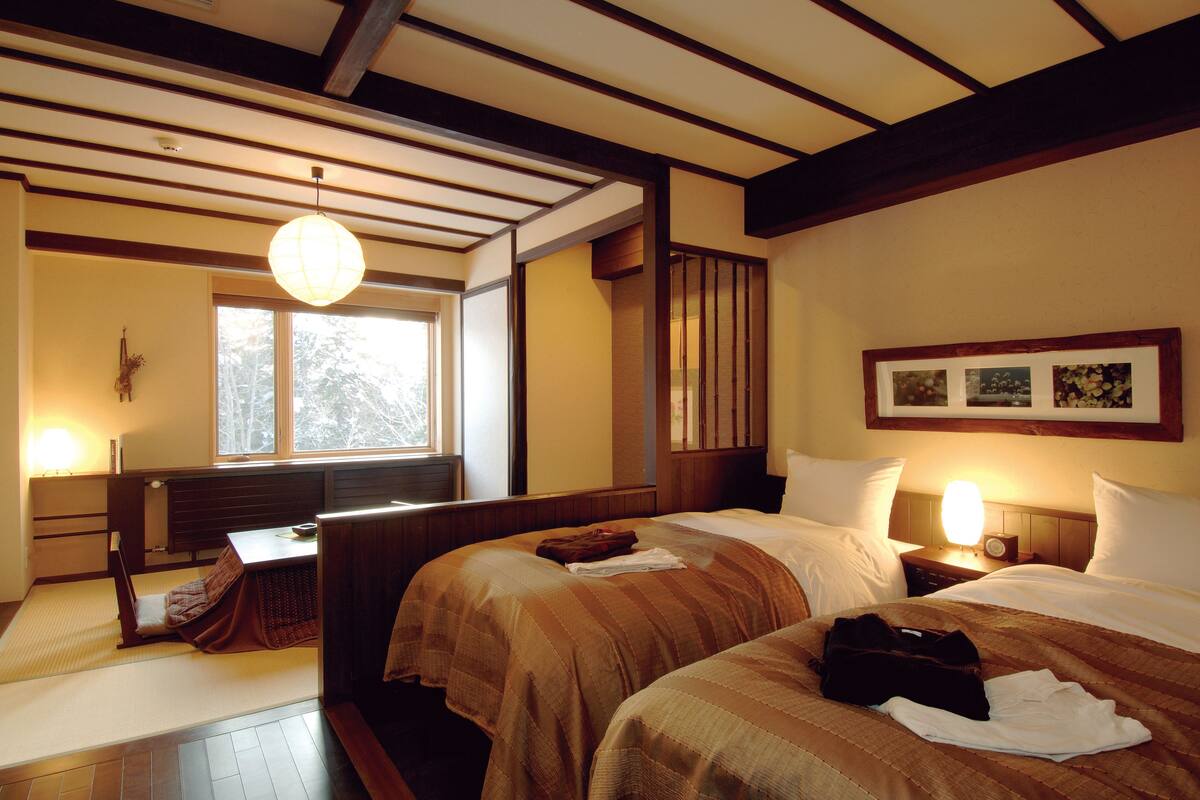 Une chambre d’hôtel avec deux lits, un bureau et une grande fenêtre.