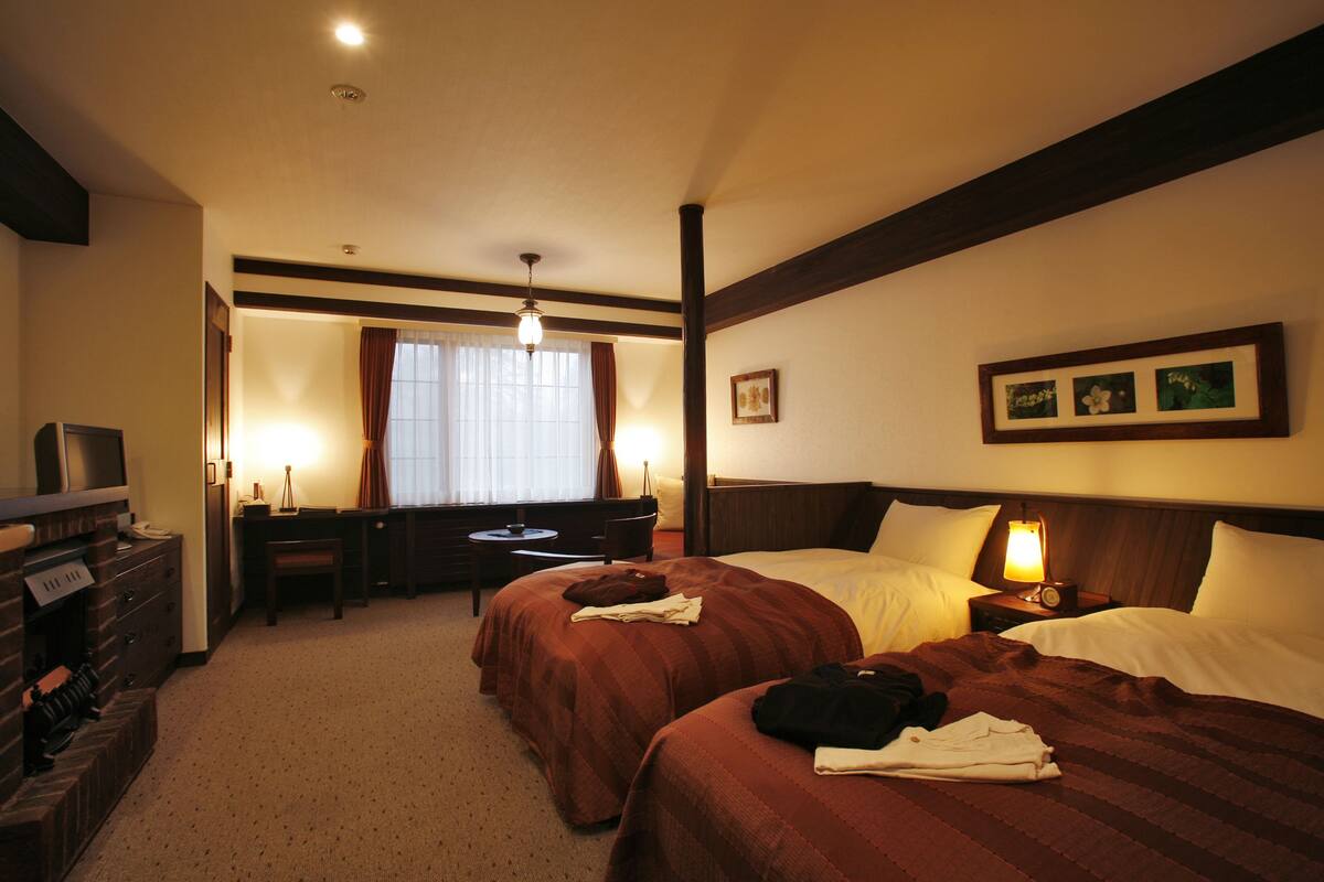 Une chambre d’hôtel avec deux lits, un bureau, une chaise et un téléviseur.