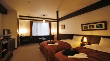 A hotel room with two beds, a desk, a chair, and a television.