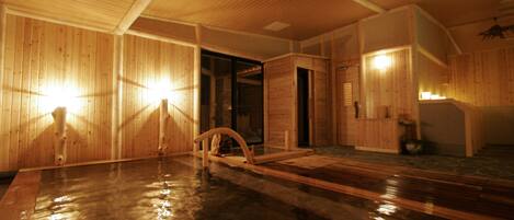 A wooden interior with a hot spring bath, wooden walls, and a wooden ceiling.