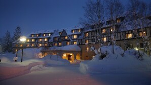 Un edificio cubierto de nieve con múltiples ventanas y una entrada iluminada.