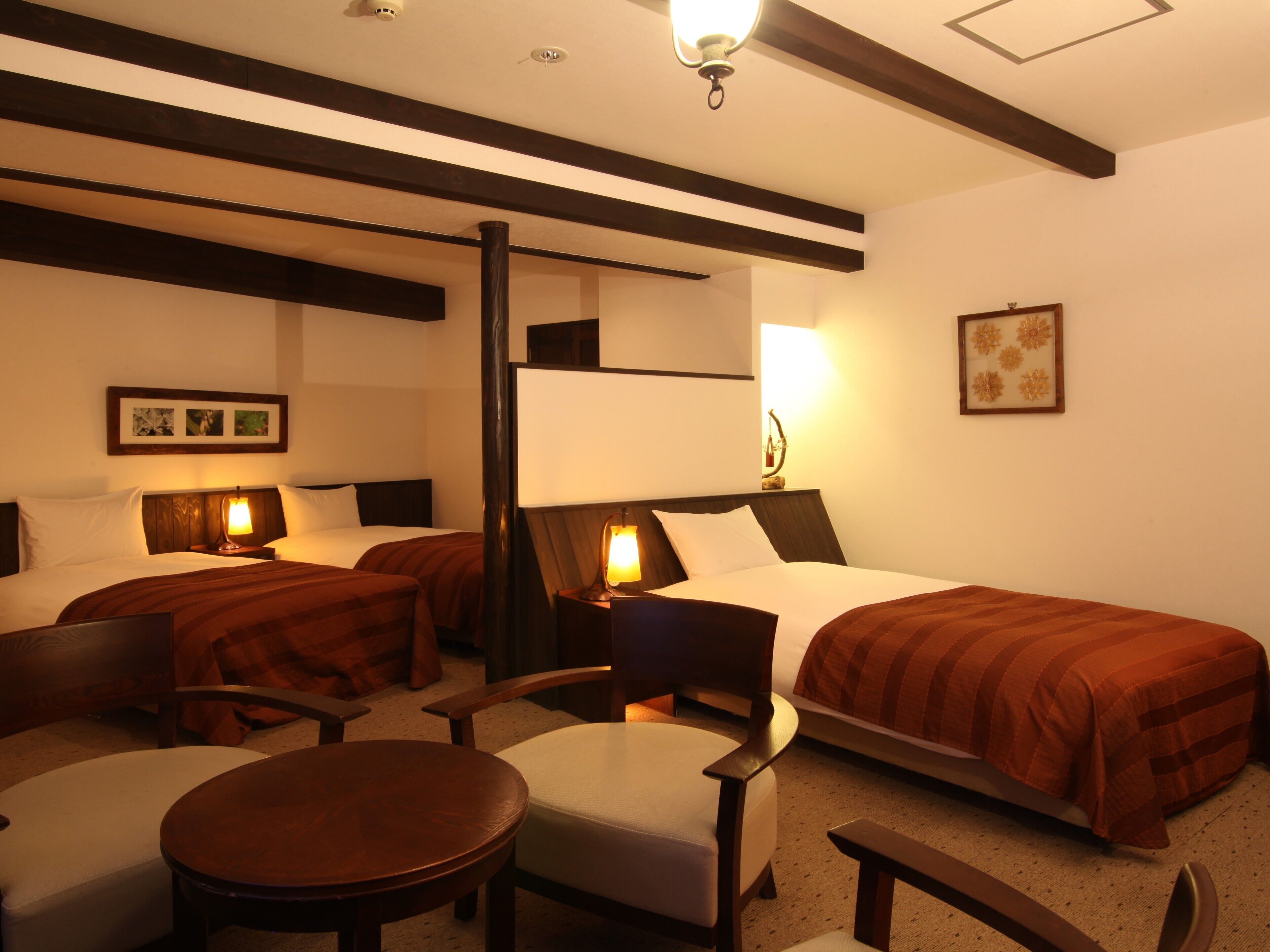 A hotel room with two beds, a desk, a chair, and a small table.