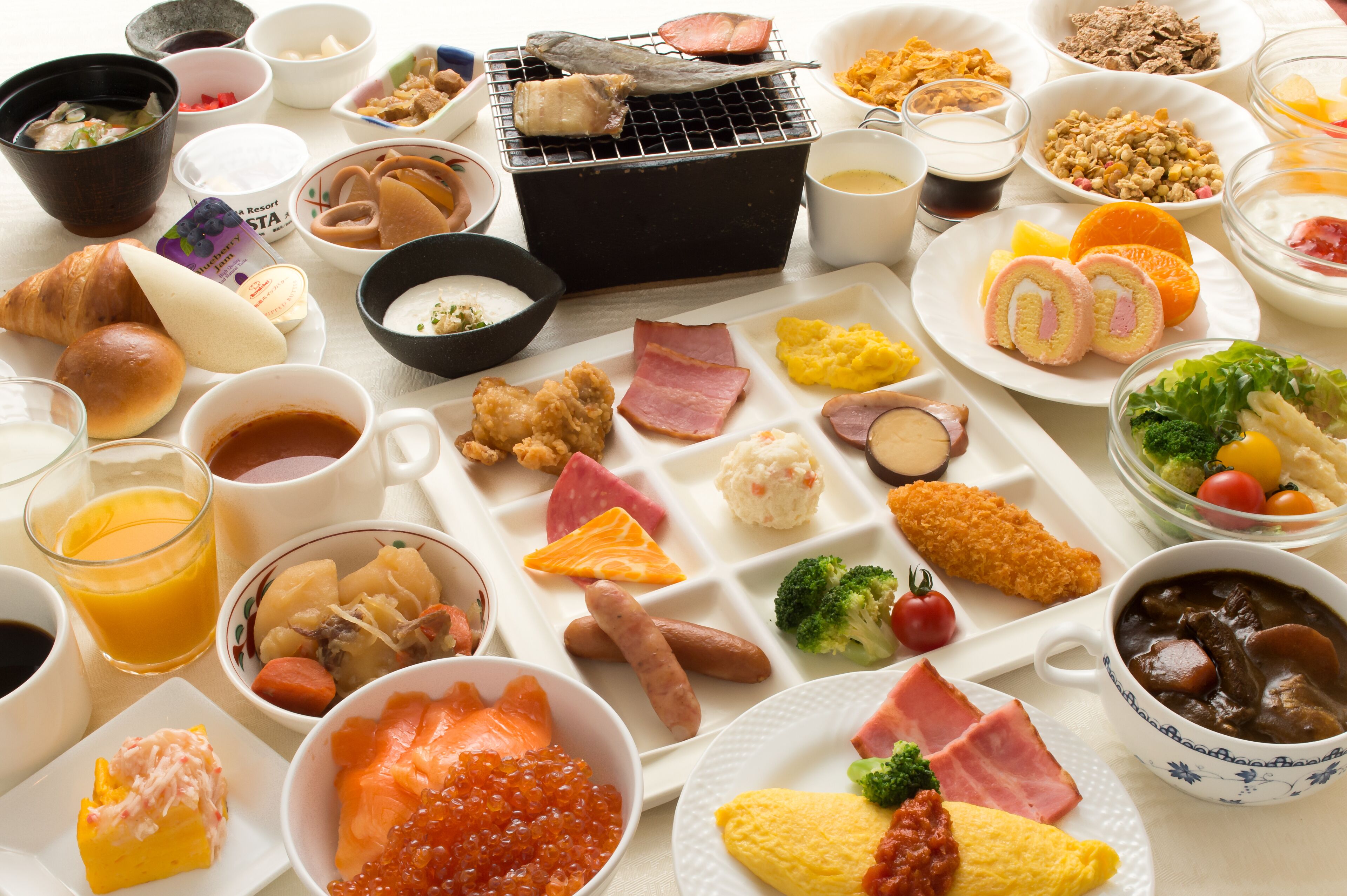 Verschiedene Frühstücksgerichte, darunter Eier, Schinken und Lachs, sind auf einem Tisch angerichtet.