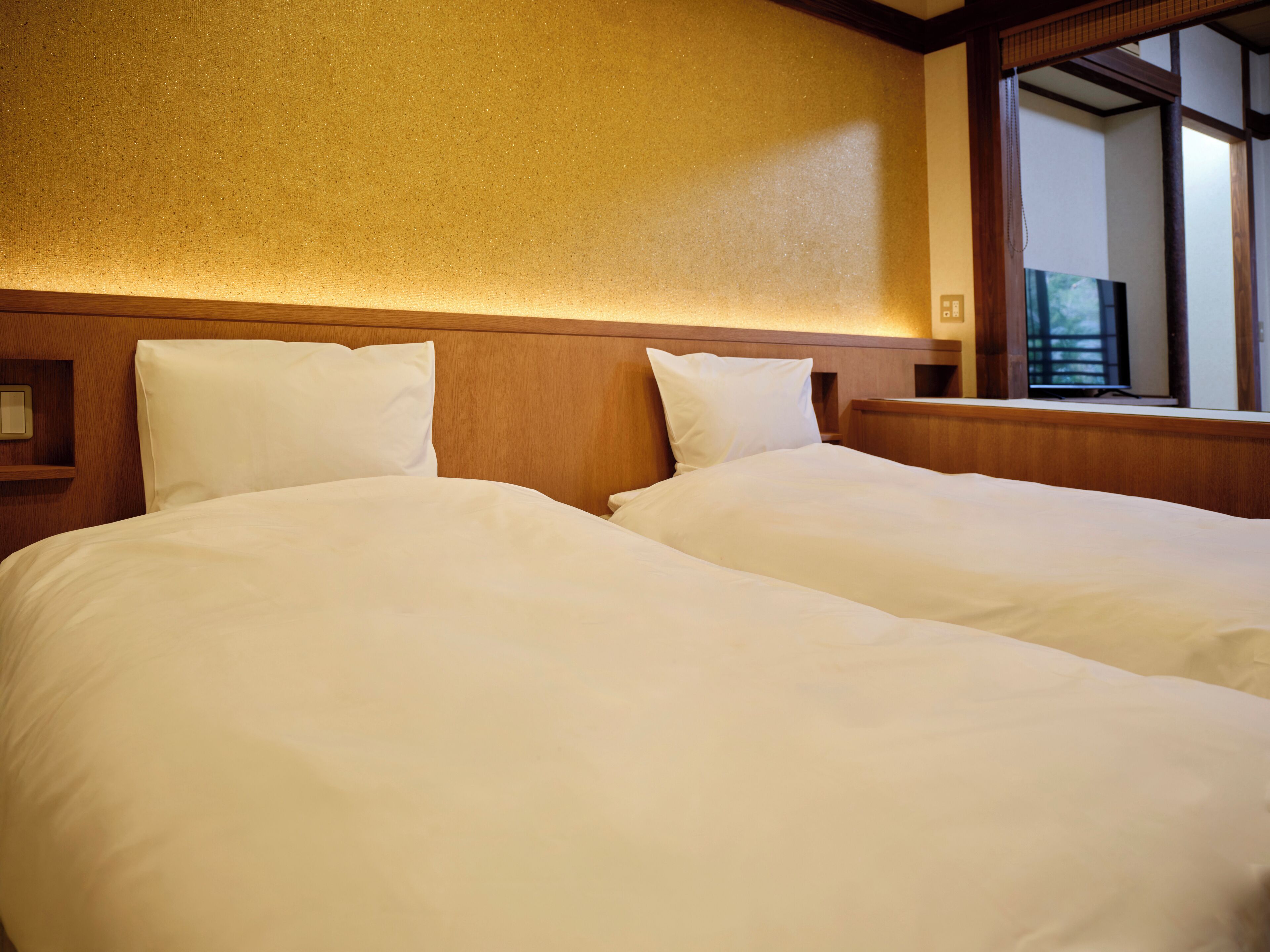 A hotel room with two beds, wooden headboard, and a large window.