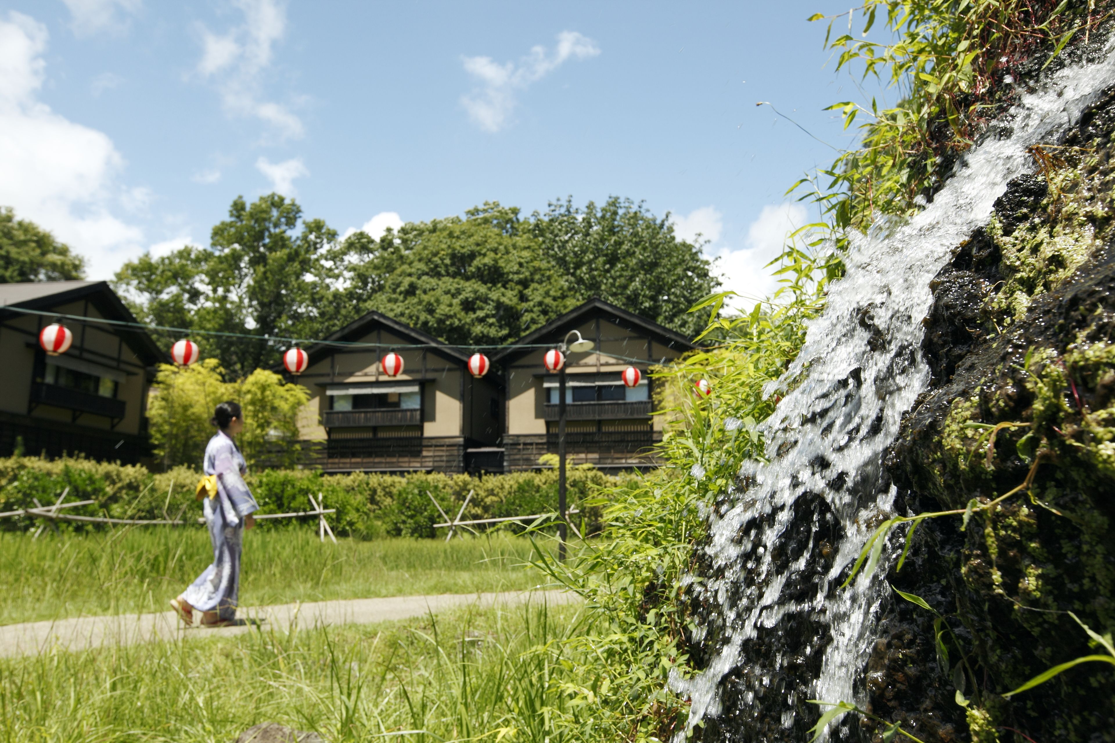 A traditional Japanese-style building with a waterfall in the foreground.
