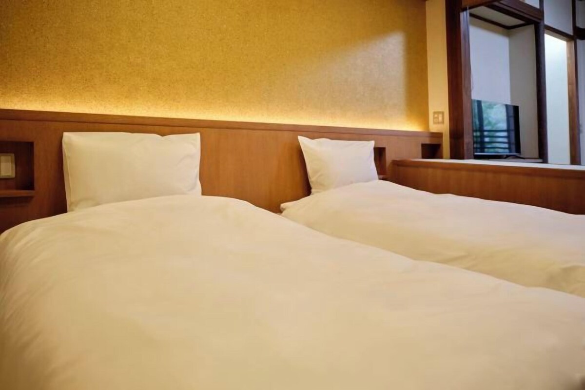 A hotel room with two beds, wooden headboard, and a large window with a view.