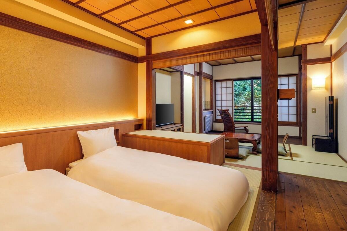 A hotel room with two beds, a television, and a traditional Japanese-style interior.