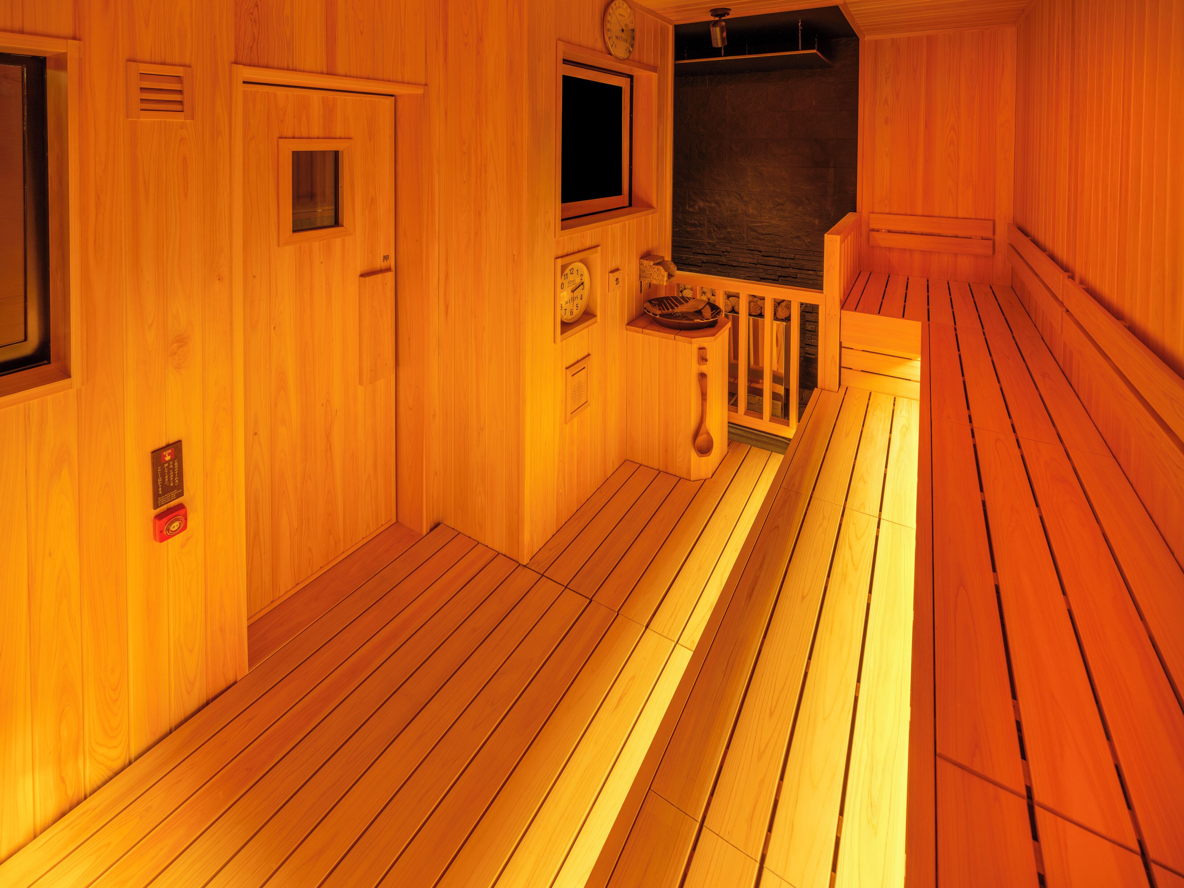 A wooden interior with a wooden floor, a bench, a clock, and a window.