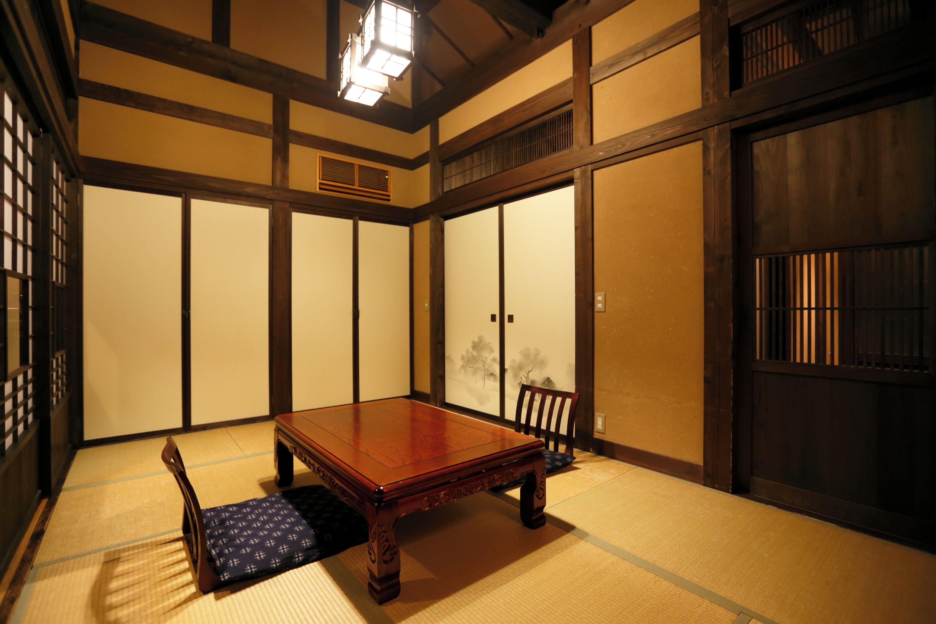 A traditional Japanese room with tatami flooring, a low wooden table, and a sliding door.