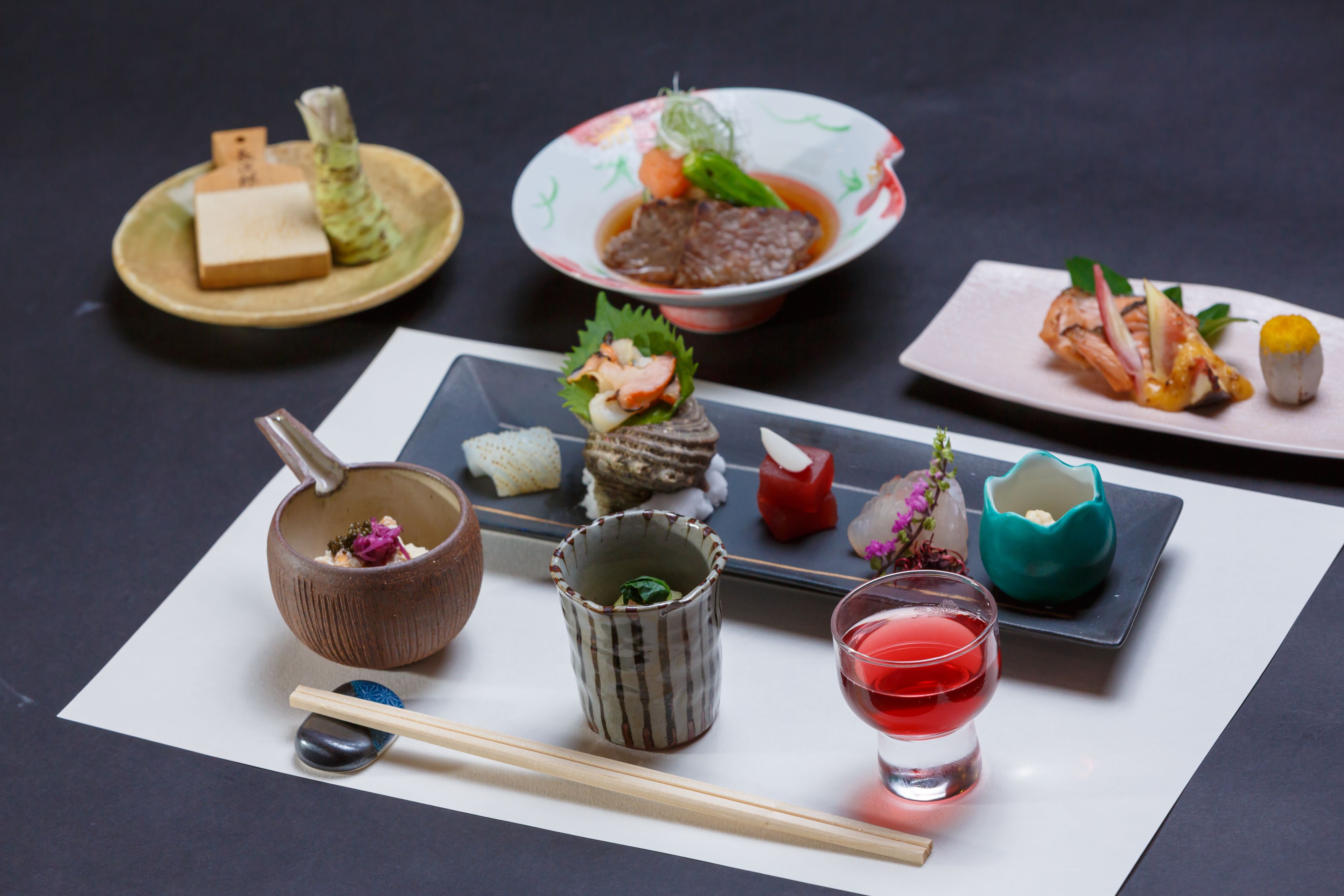 Eine Auswahl japanischer Gerichte auf einem Tisch, darunter Sushi, Sashimi und eine Suppenschüssel.